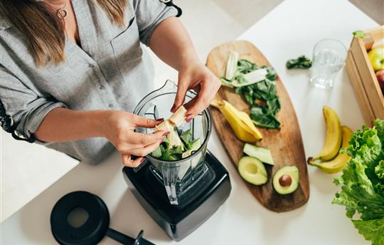 woman making a smoothie with a blender